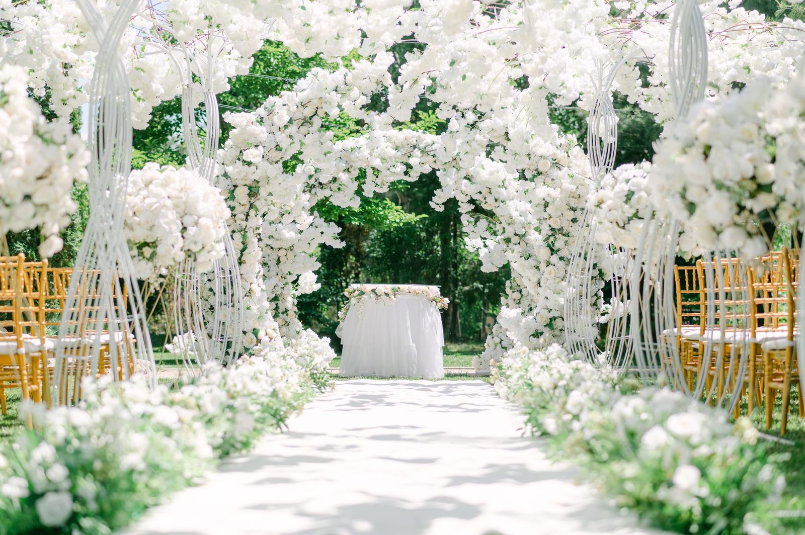 A white floral aisle beneath hanging blooms