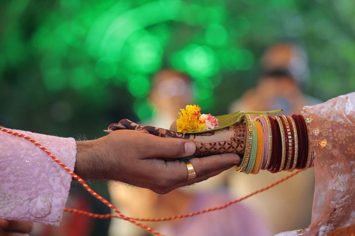 Mehendi-covered hands holding marigold